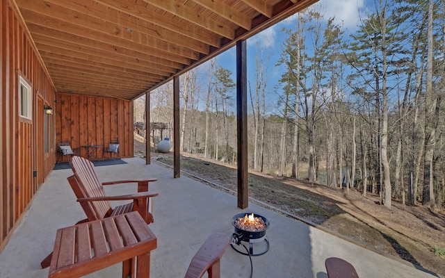 view of patio featuring an outdoor fire pit and a view of trees