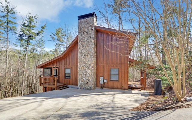 view of side of property with board and batten siding, a chimney, and a deck