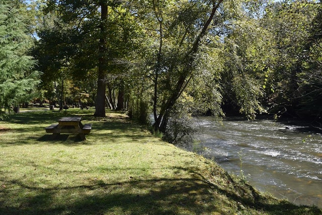 view of property's community with a lawn and a wooded view