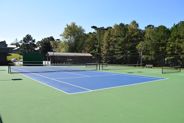 view of tennis court with community basketball court and fence