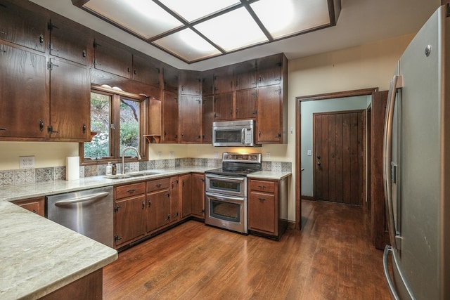 kitchen with stainless steel appliances, a sink, dark wood-style flooring, and light countertops