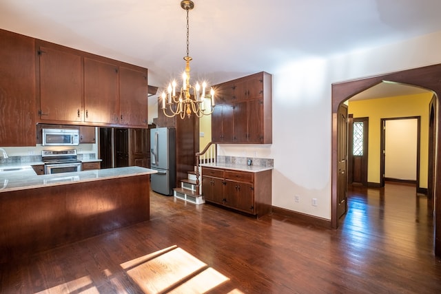 kitchen with appliances with stainless steel finishes, arched walkways, a chandelier, a sink, and dark wood-type flooring