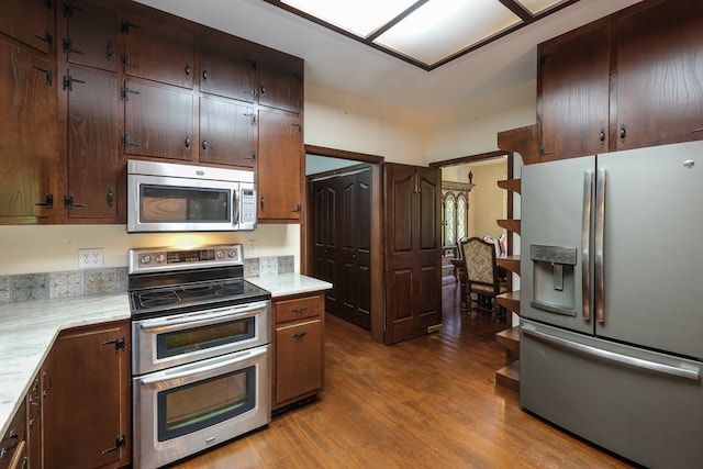 kitchen featuring appliances with stainless steel finishes, wood finished floors, and dark brown cabinetry