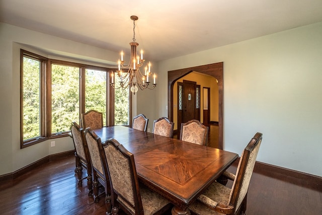 dining room featuring a chandelier, arched walkways, baseboards, and dark wood-style floors