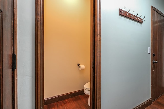 bathroom with toilet, wood finished floors, and baseboards
