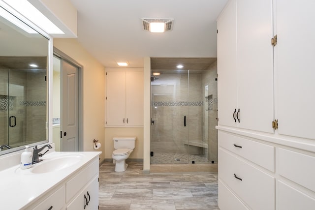full bathroom featuring toilet, vanity, a shower stall, baseboards, and recessed lighting