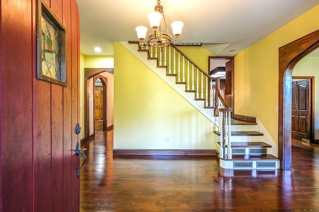 foyer with arched walkways, stairway, a chandelier, and hardwood / wood-style flooring