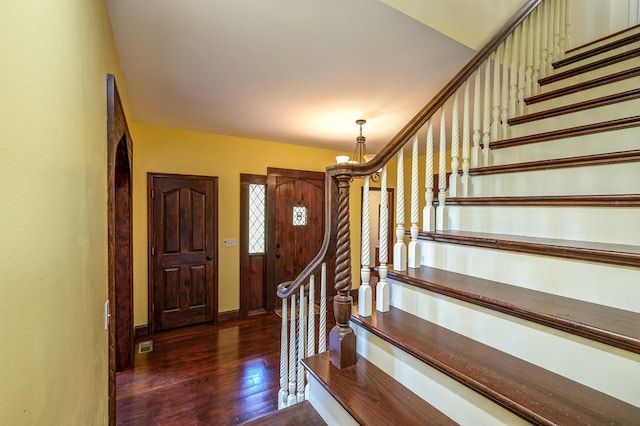 entrance foyer featuring wood-type flooring, stairs, a chandelier, and baseboards