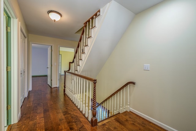 corridor featuring wood finished floors, baseboards, and an upstairs landing