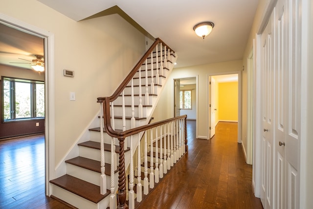 staircase featuring hardwood / wood-style flooring, ceiling fan, and baseboards