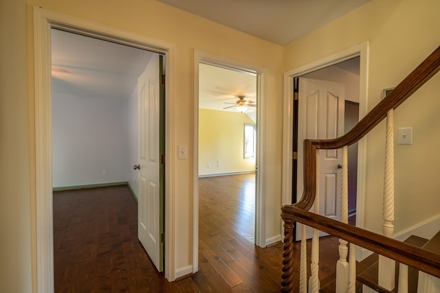 corridor with dark wood-style flooring and baseboards
