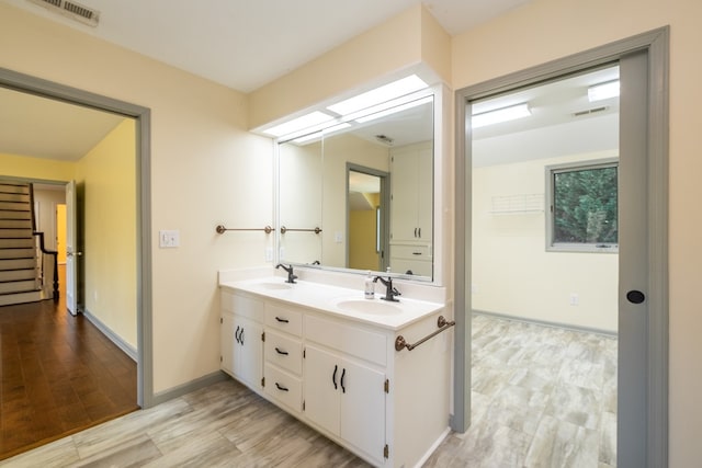 bathroom with double vanity, wood finished floors, and baseboards