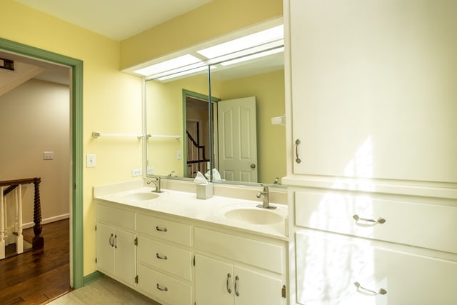 bathroom featuring double vanity, wood finished floors, and baseboards