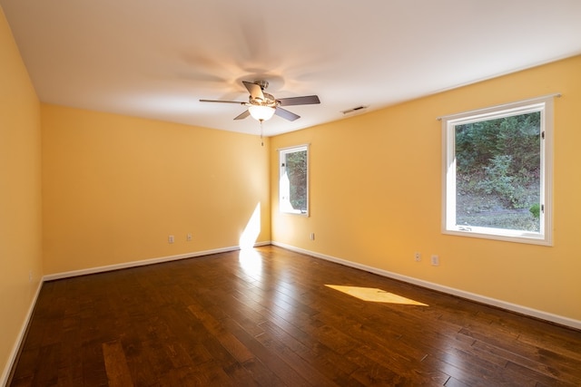 unfurnished room featuring dark wood-type flooring, a ceiling fan, and baseboards