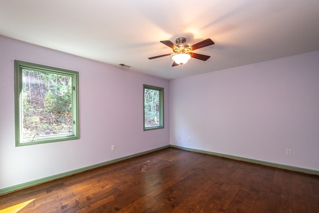 empty room featuring plenty of natural light, a ceiling fan, wood-type flooring, and baseboards