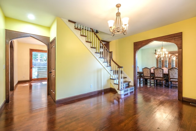 stairs with a chandelier, arched walkways, wood finished floors, and baseboards