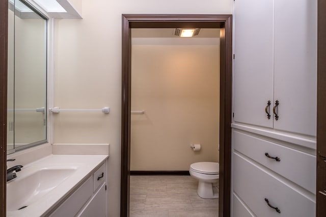 bathroom featuring toilet, vanity, and baseboards