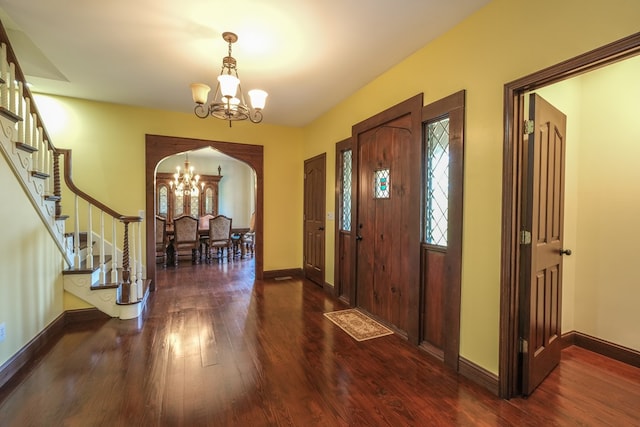 foyer with a chandelier, arched walkways, stairway, and wood finished floors