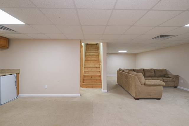 living room with light carpet, stairway, baseboards, and a drop ceiling