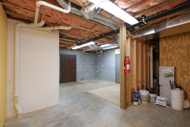 unfinished basement featuring concrete block wall