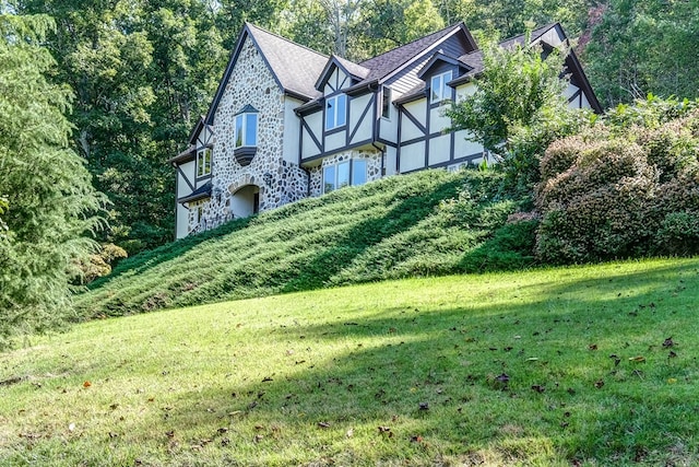 view of front of house with stucco siding, stone siding, and a front lawn