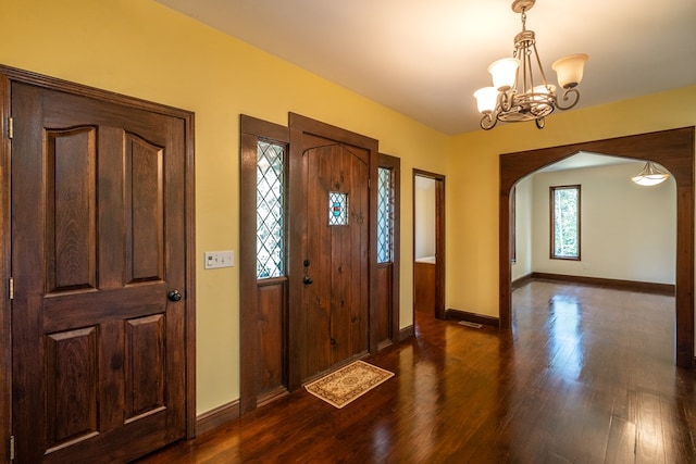 entryway with arched walkways, a chandelier, dark wood-style floors, and baseboards