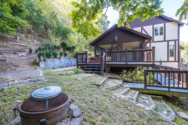 rear view of house with a wooden deck, a sunroom, an outdoor fire pit, and stucco siding