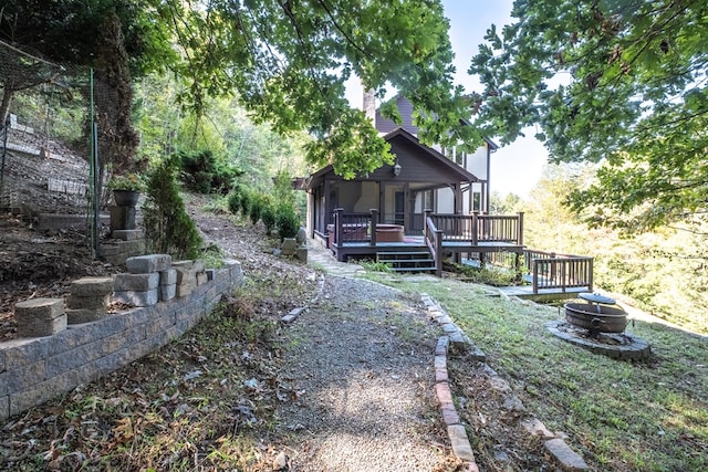 rear view of house with a fire pit and a wooden deck