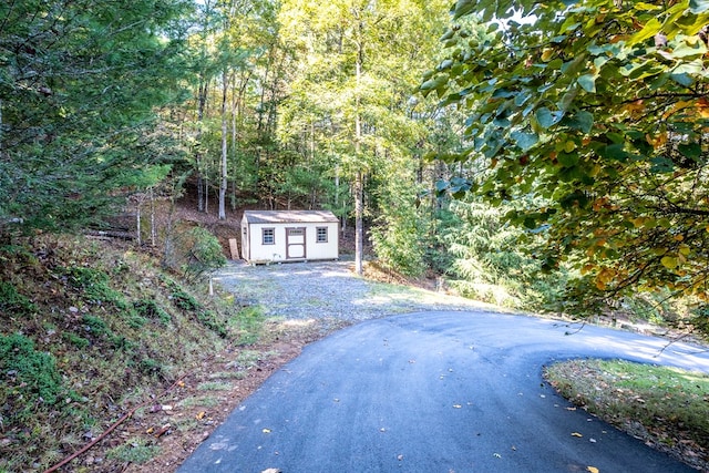 view of asphalt driveway featuring a wooded view