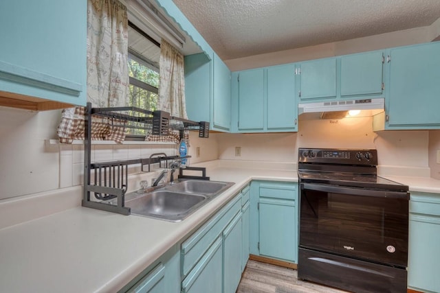 kitchen featuring blue cabinets, under cabinet range hood, a sink, black range with electric cooktop, and light countertops