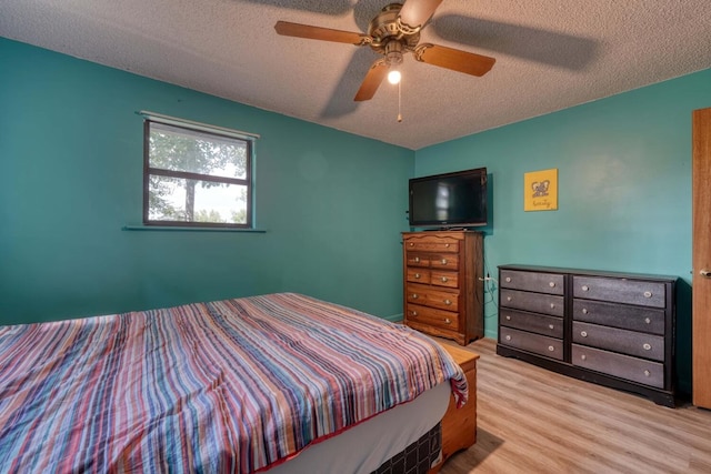 bedroom with a textured ceiling, ceiling fan, and hardwood / wood-style flooring