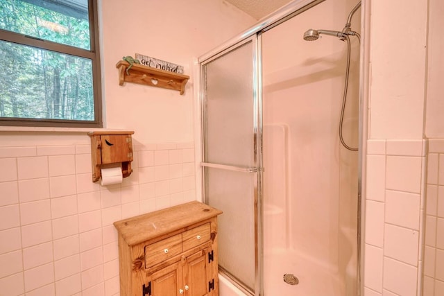 full bathroom with a wainscoted wall, a shower stall, and tile walls