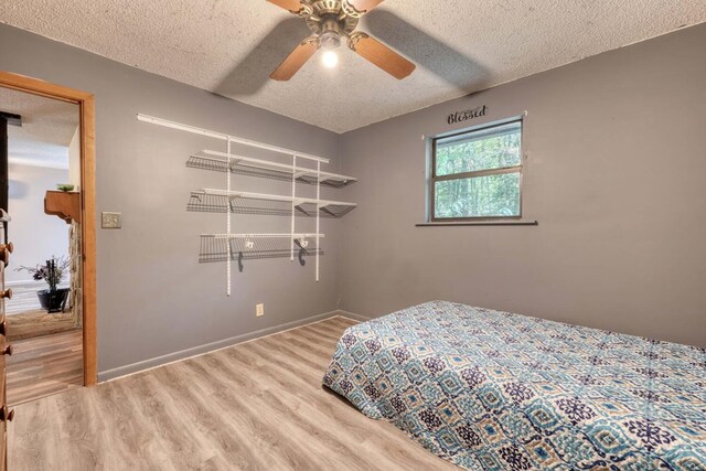 bedroom with a textured ceiling, hardwood / wood-style flooring, and ceiling fan