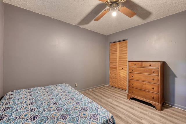 bedroom with a closet, baseboards, a textured ceiling, and light wood-style flooring