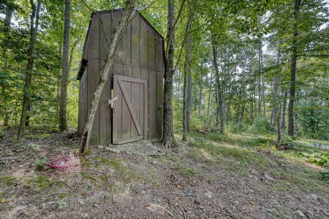 view of outbuilding featuring a wooded view and an outdoor structure