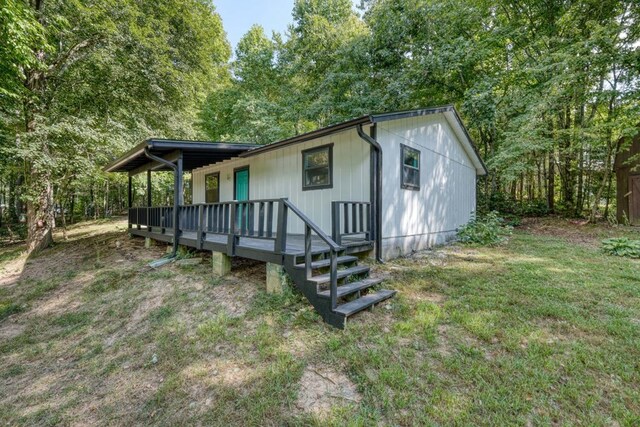 rear view of property with a wooden deck and a lawn