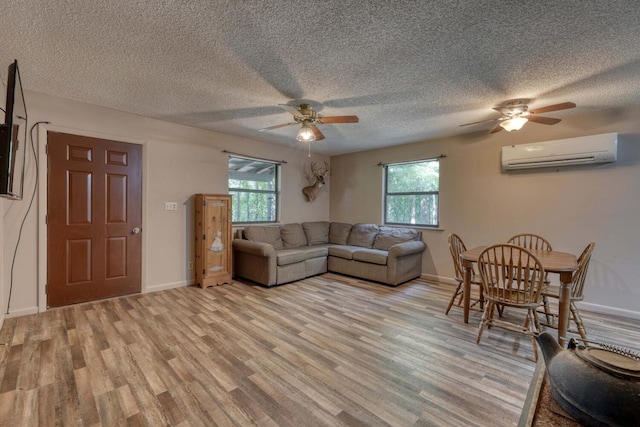 living room with baseboards, a healthy amount of sunlight, light wood-style flooring, and a wall mounted AC