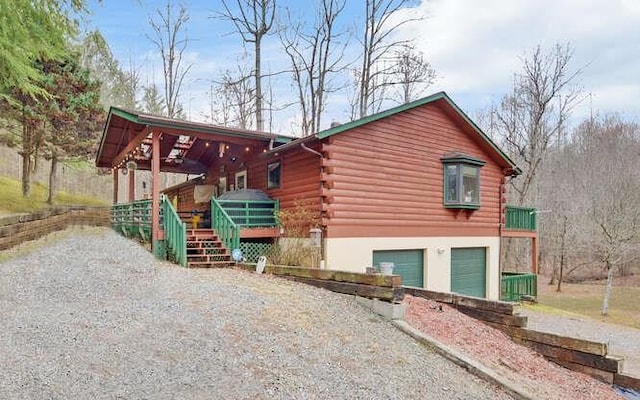 view of side of property featuring log siding, gravel driveway, and an attached garage