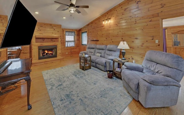 living room with a large fireplace, lofted ceiling, a ceiling fan, and wood finished floors