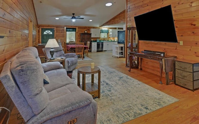 living area featuring high vaulted ceiling, recessed lighting, ceiling fan, light wood-style floors, and wood walls