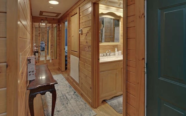 hall featuring attic access, light wood-style flooring, and a sink