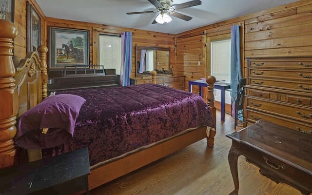 bedroom with wood walls, ceiling fan, and wood finished floors