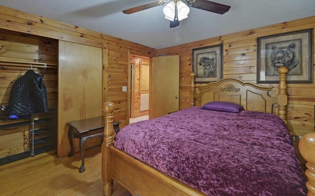 bedroom featuring wooden walls, wood finished floors, and a ceiling fan