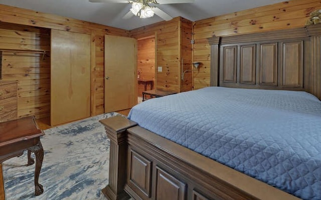 bedroom with ceiling fan, two closets, and wood walls