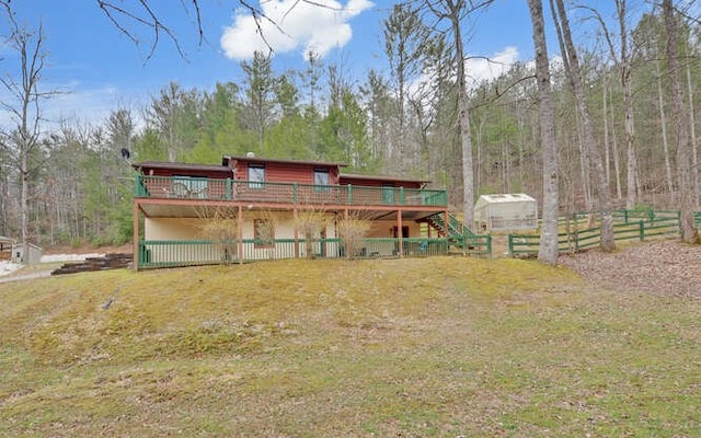 back of house featuring fence, a wooded view, and a wooden deck