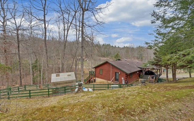 exterior space featuring an outbuilding, fence private yard, and a view of trees