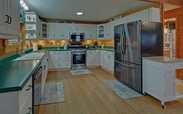 kitchen featuring a sink, light wood-style flooring, glass insert cabinets, and stainless steel appliances