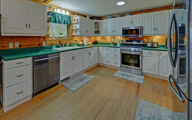 kitchen with light wood-style flooring, white cabinets, stainless steel appliances, and a sink