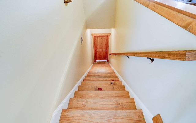 stairway featuring light wood-type flooring and a towering ceiling