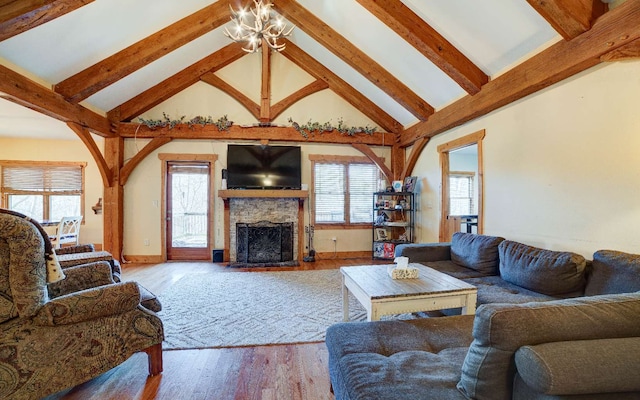 living room with an inviting chandelier, beam ceiling, a stone fireplace, and light hardwood / wood-style flooring